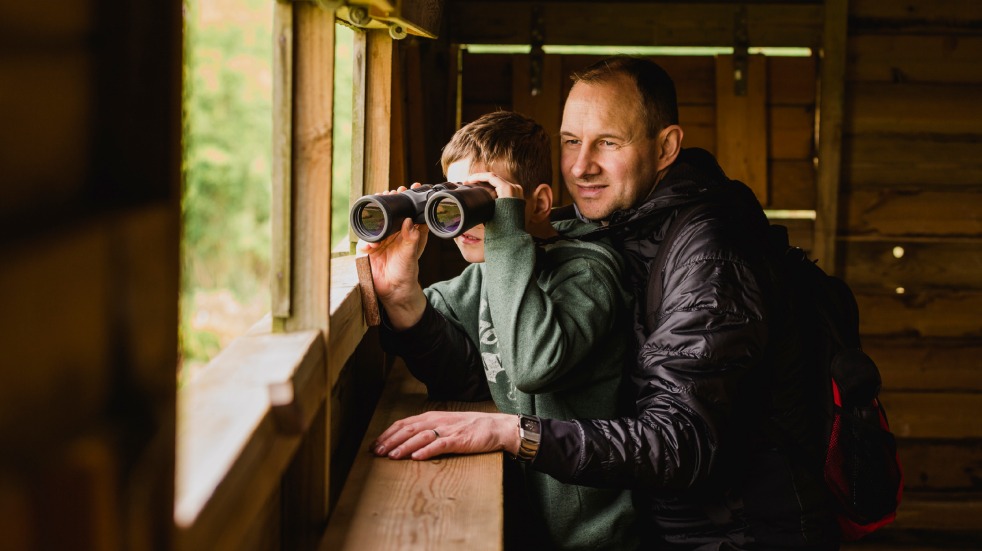 Man and boy birdwatching in hide